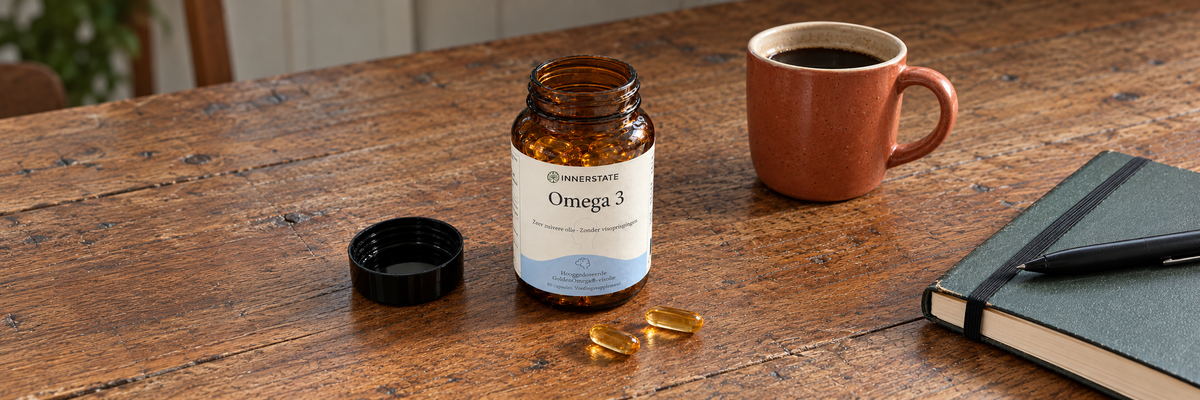 Open potje Innerstate Omega-3 met capsules op tafel, naast een koffiemok en notitieboek