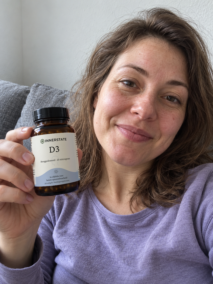 Vrouw op de bank met een pot Innerstate vitamine D3 in haar hand