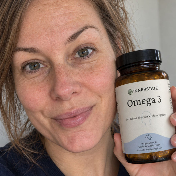 Vrouw met een pot Innerstate Omega-3 naast haar gezicht