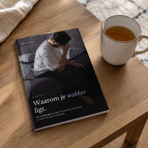 De Innerstate slaapgids op een houten tafel naast een kop thee in een rustige setting