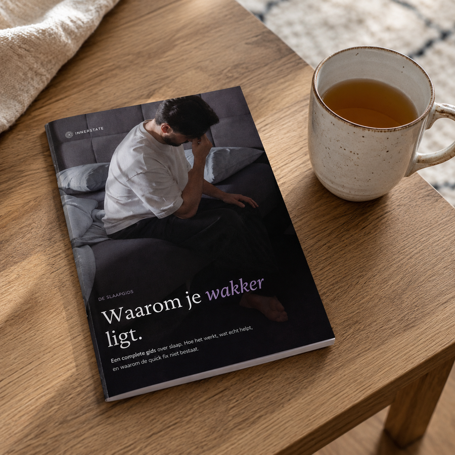 De Innerstate slaapgids op een houten tafel naast een kop thee in een rustige setting